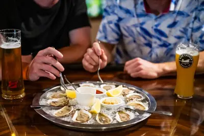 a plate of oysters on a table with two people at Georgian Bay Hotel Trademark Collection by Wyndham in Collingwood