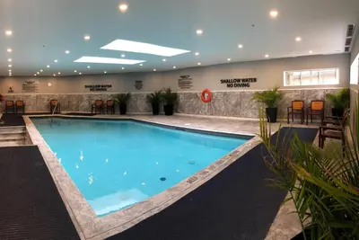 a large swimming pool in a building with chairs at Georgian Bay Hotel Trademark Collection by Wyndham in Collingwood