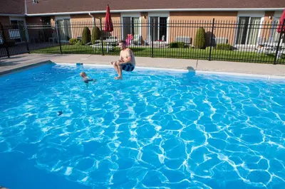 a man and a baby playing in a blue swimming pool at Super 8 by Wyndham Port Elgin in Port Elgin