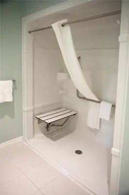 a bathroom with a shower with a bench in it at Super 8 by Wyndham Port Elgin in Port Elgin