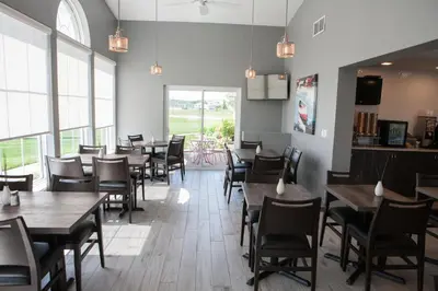 a dining room with tables and chairs and windows at Super 8 by Wyndham Port Elgin in Port Elgin