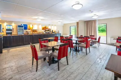 a restaurant with red chairs and tables and a counter at Comfort Inn in Midland