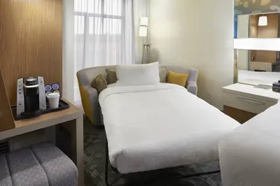 a hotel room with a bed and a chair at Courtyard by Marriott Oshawa in Oshawa
