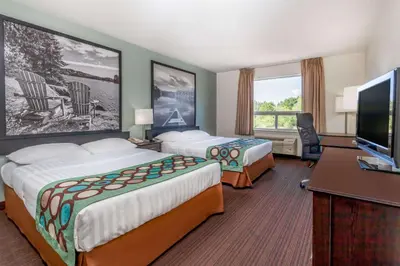 a hotel room with two beds and a flat screen tv at Super 8 by Wyndham Peterborough in Peterborough