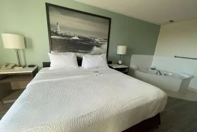 a bedroom with a large bed and a bath tub at Super 8 by Wyndham Peterborough in Peterborough