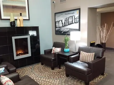 a waiting room with leather chairs and a fireplace at Super 8 by Wyndham Peterborough in Peterborough
