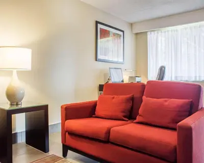 a living room with a red couch and a lamp at Comfort Inn in Brantford