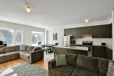 a kitchen and living room with couches and a table at New Blue Mountain Village Snowbridge Executive Townhome Sleeps 10 with Outdoor Pool and Shuttle in Nottawa