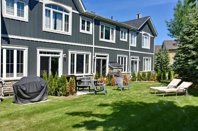 a house with a yard with chairs in front of it at New Blue Mountain Village Snowbridge Executive Townhome Sleeps 10 with Outdoor Pool and Shuttle in Nottawa