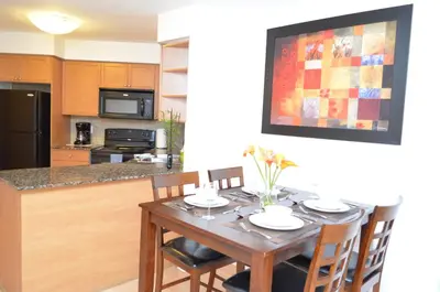 a kitchen with a wooden table with chairs and a dining room at Bombay Suites Mississauga in Mississauga