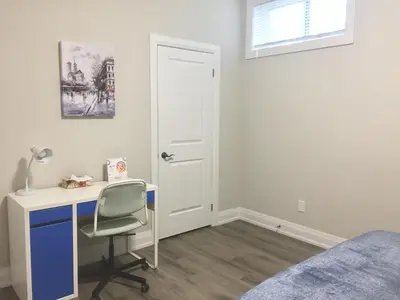 a bedroom with a desk and a bed and a window at Charming, Comfortable Bsmt Apartment in Pickering in Pickering
