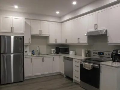 a kitchen with white cabinets and a stainless steel refrigerator at Charming, Comfortable Bsmt Apartment in Pickering in Pickering
