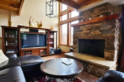 a living room with a fireplace and a leather couch at Blue Mountain-Luxurious BlueSki George Chalet, Hot Tub, Pool, Gas Fireplace in Blue Mountains