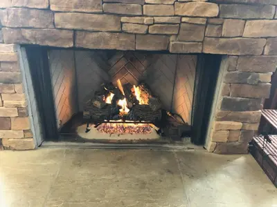 a brick fireplace with a fire in it at Blue Mountain-Luxurious BlueSki George Chalet, Hot Tub, Pool, Gas Fireplace in Blue Mountains