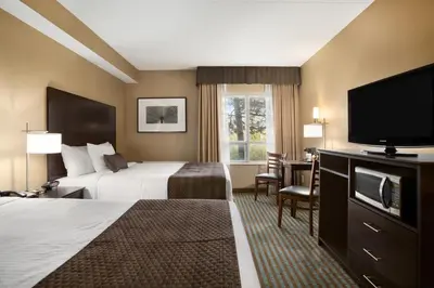a hotel room with two beds and a flat screen tv at Days Inn by Wyndham Stouffville in Stouffville