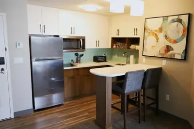 a kitchen with a refrigerator and a table at Staybridge Suites - Waterloo - St. Jacobs Area in Waterloo