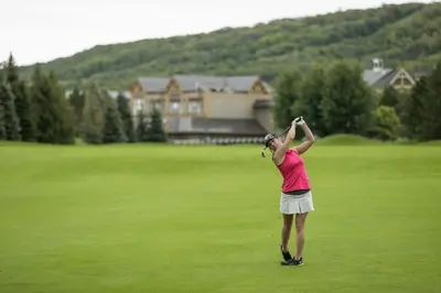 a woman standing on a golf course holding a club at Blue Mountain Resort Inn in Blue Mountains