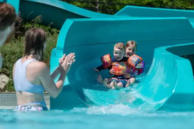 a woman and two children on a water slide at Blue Mountain Resort Mosaic Suites in Blue Mountains