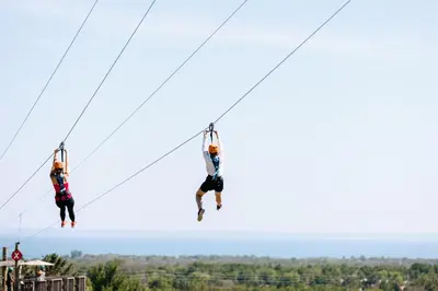 two people are jumping on a zip line at Blue Mountain Resort Mosaic Suites in Blue Mountains