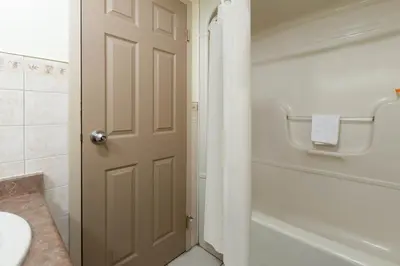 a bathroom with a door and a tub and a sink at Super 8 by Wyndham Niagara Falls by the Falls in Niagara Falls