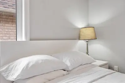 a white bed with two pillows and a lamp at Amazing Spacious house in Center of Richmond hill in Richmond Hill