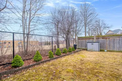 a fence with a row of bushes in a yard at Amazing Spacious house in Center of Richmond hill in Richmond Hill