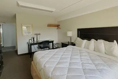 a hotel room with a large white bed and a desk at Travelodge by Wyndham Welland in Welland