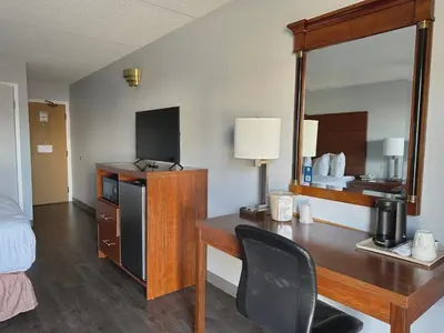 a hotel room with a desk and a mirror at Travelodge by Wyndham Welland in Welland