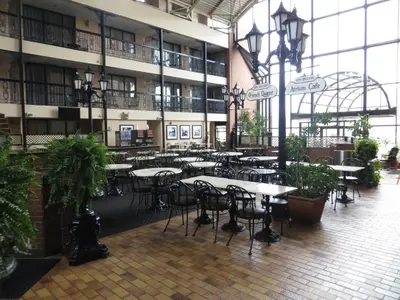 a cafeteria with tables and chairs in a building at Clifton Victoria Inn at the Falls in Niagara Falls