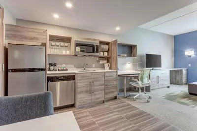 a kitchen with a refrigerator and a table and chairs at Home2 Suites By Hilton Toronto/Brampton, On in Brampton