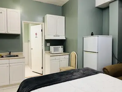 a kitchen with white cabinets and a white refrigerator at Saint Lawrence Residences and Suites in Toronto