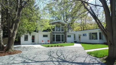 a white house with trees in front of it at Carriage House On Kent in Niagara on the Lake