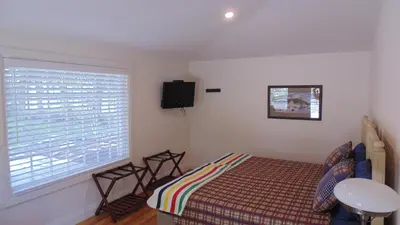 a bedroom with a bed and a tv and a window at Carriage House On Kent in Niagara on the Lake