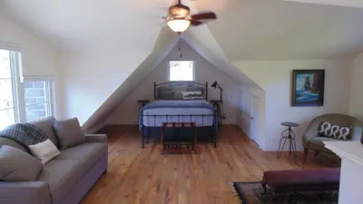 a living room with a bed with a ceiling fan at Carriage House On Kent in Niagara on the Lake