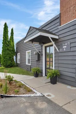 a gray house with a porch with plants at The Bloomfield Inn in Bloomfield