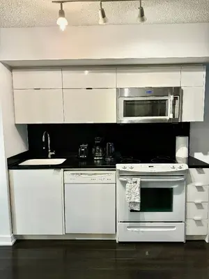 a kitchen with white appliances and a microwave at Cozy Condo near CN Tower in Toronto