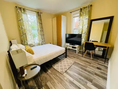 a bedroom with a bed and a desk and a television at Comfortable and Convenient Apartment in Central Niagara in St. Catharines