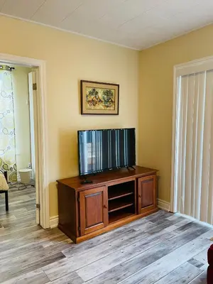 a living room with a flat screen tv on a wooden entertainment center at Comfortable and Convenient Apartment in Central Niagara in St. Catharines