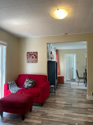 a living room with a red couch and a chair at Comfortable and Convenient Apartment in Central Niagara in St. Catharines