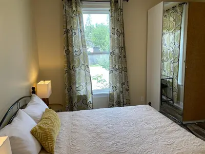 a bedroom with a bed and a window at Comfortable and Convenient Apartment in Central Niagara in St. Catharines