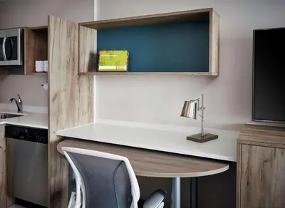 a kitchen with a desk and a table and a tv at Home2 Suites By Hilton Brantford in Brantford