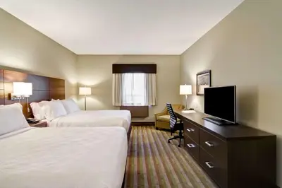 a hotel room with two beds and a desk with a television at Best Western London Airport Inn & Suites in London