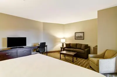 a hotel room with a bed and a couch and a television at Best Western London Airport Inn & Suites in London