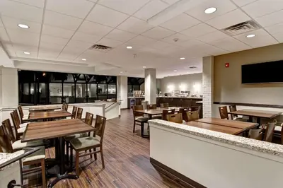 a restaurant with wooden tables and chairs and a bar at Best Western London Airport Inn & Suites in London