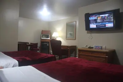 a hotel room with two beds and a flat screen tv at American Plaza Motel in London