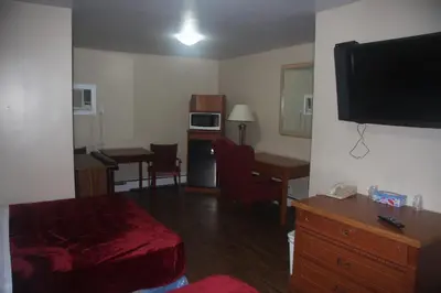 a room with a living room with a bed and a television at American Plaza Motel in London