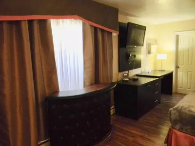 a hotel room with a bed and a desk and a window at American Plaza Motel in London