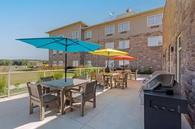 a patio with tables and umbrellas and a grill at Best Western Plus Walkerton Hotel & Conference Centre in Walkerton