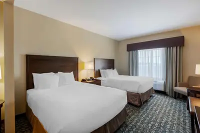 a hotel room with two beds and a couch at Best Western Plus Walkerton Hotel & Conference Centre in Walkerton