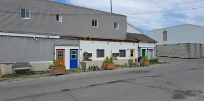 a white building with chairs and plants in front of it at Campbellford Studio Apt 4 in Campbellford